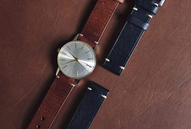 นาฬิกาคลาสสิกที่มีสายหนังสีน้ำตาลและสายหนังสีดำอยู่ข้างๆ สำหรับการเลือกสายนาฬิกาที่เหมาะสม