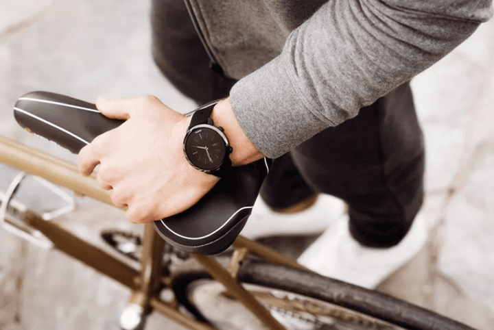 ชายกำลังขึ้นจักรยาน สวมนาฬิกาอัจฉริยะสำหรับฟิตเนสสีดำ